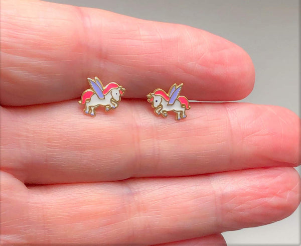 Unicorn earrings being held in hand