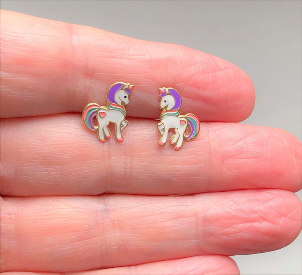 Unicorn earrings being held by a hand